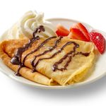 freshly baked crepe with strawberries and whipped cream isolated on white background